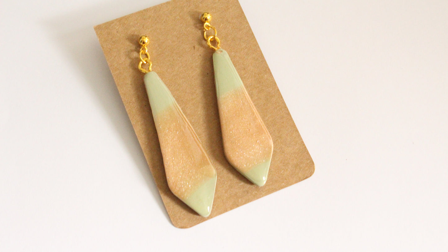 Teardrop-shaped earrings on a cardboard backing with a beige background