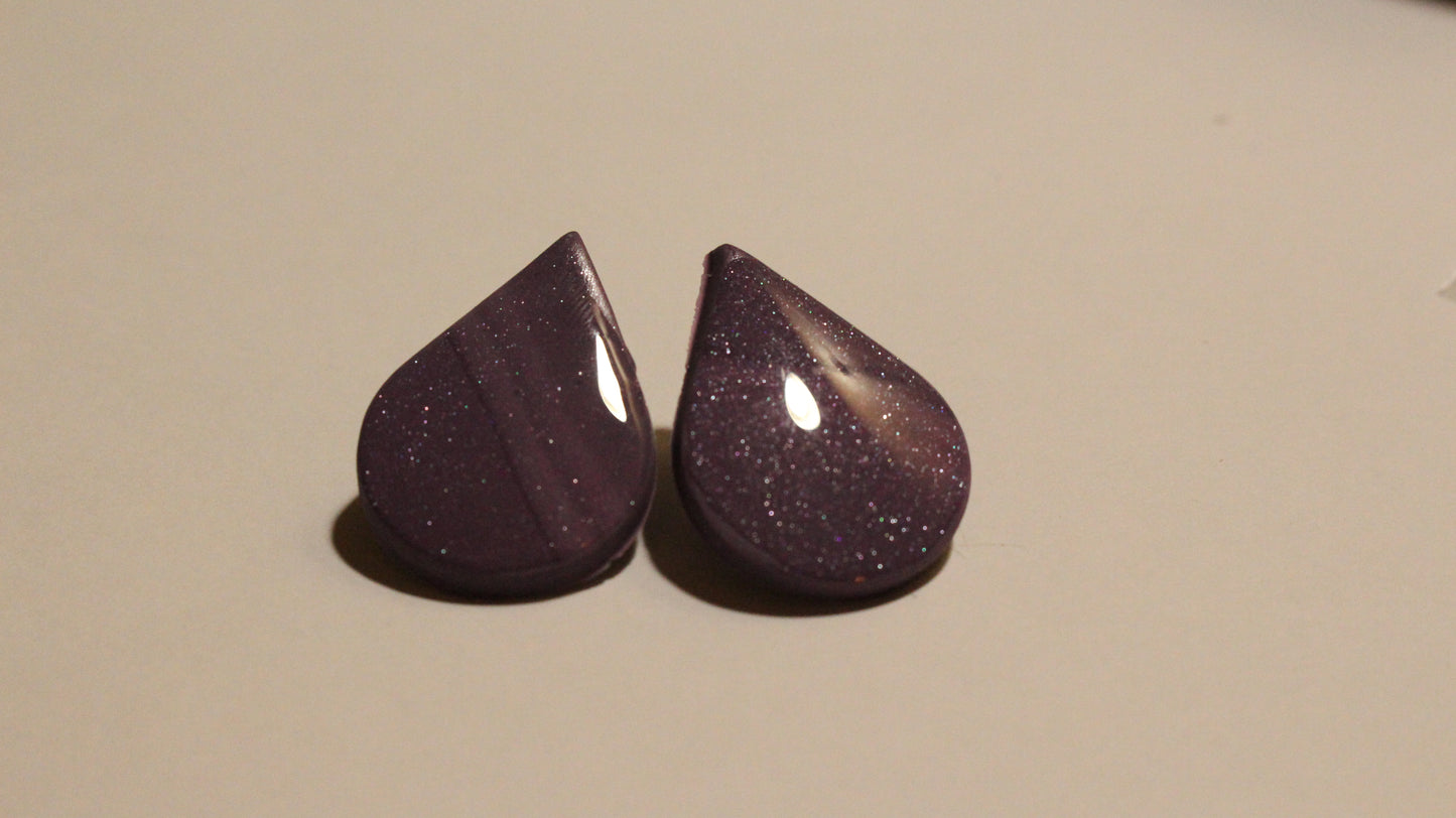 Pair of purple teardrop-shaped earrings on a beige background