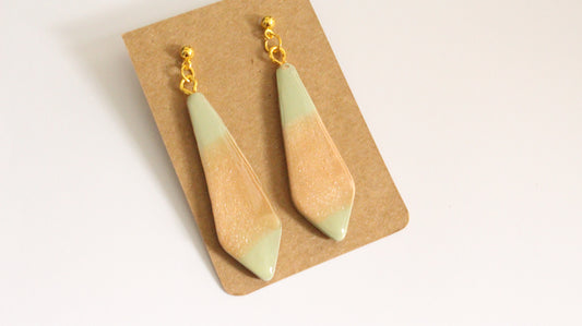 Teardrop-shaped earrings on a cardboard backing with a beige background