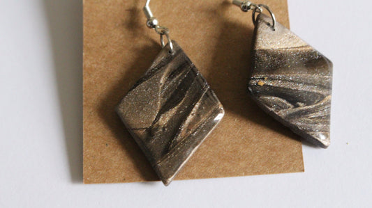 Bronze square earrings on a brown card with a white background
