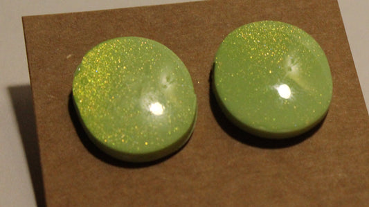 Pair of green earrings on a brown card with a beige background