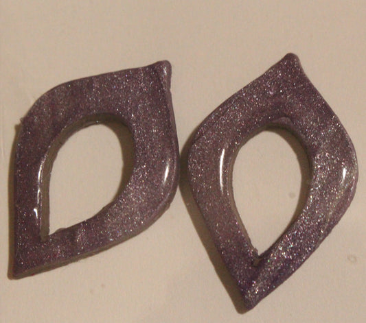 Pair of purple glittery earrings on a beige background