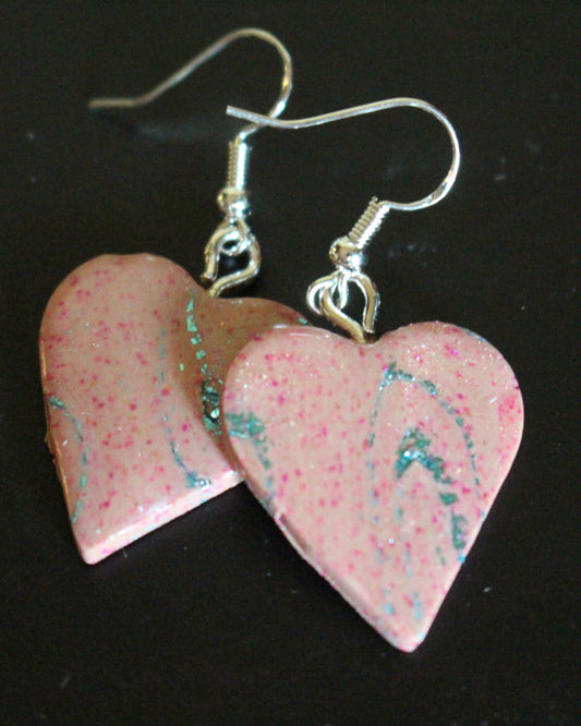 Heart-shaped earrings with pink and blue marbled design on a black background