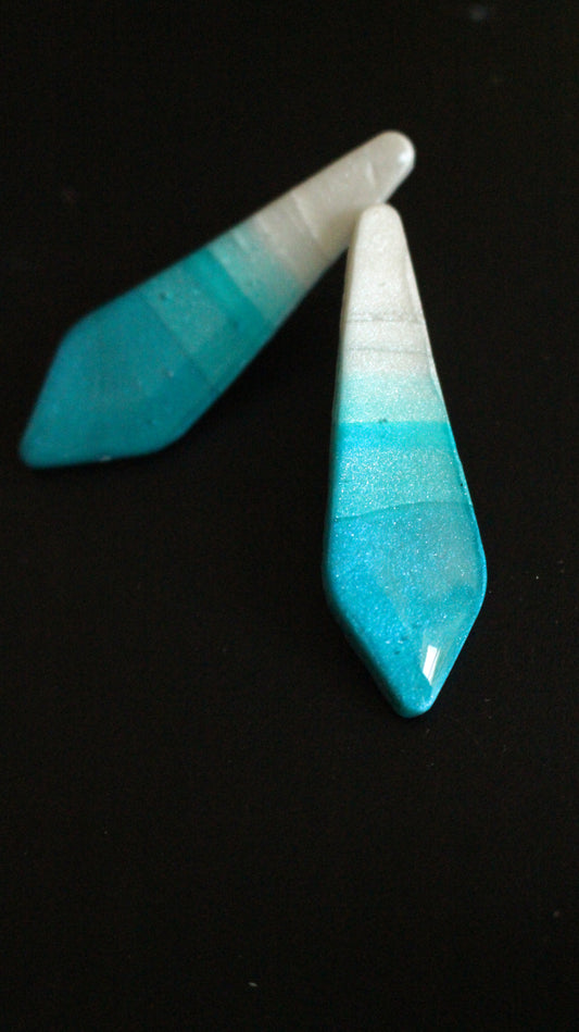 Two blue and white ceramic teardrop-shaped objects on a black background