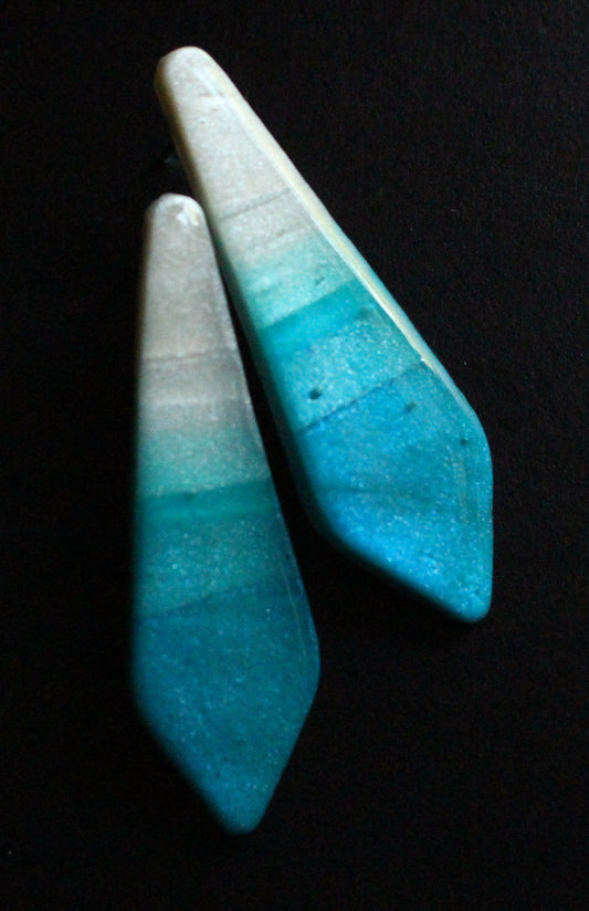 Two blue stone pendants on a black background