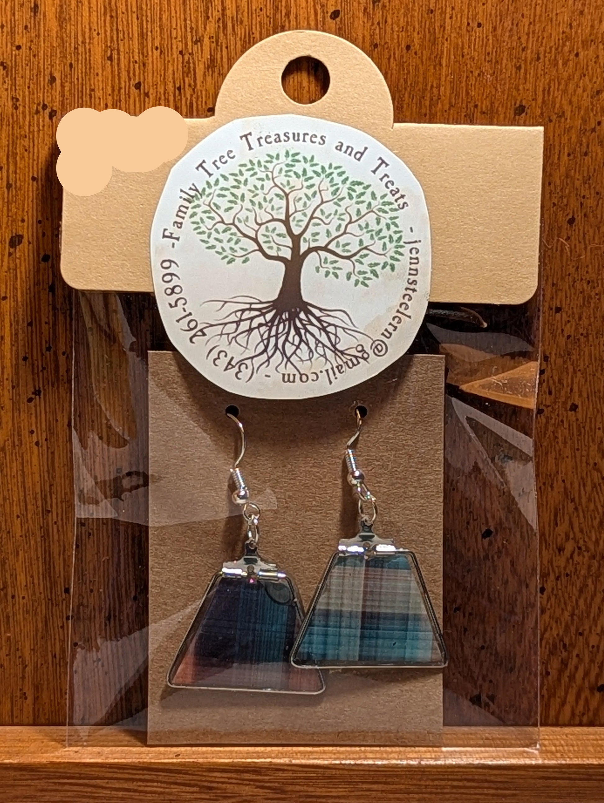 Pair of triangle-shaped earrings on a wooden display card with a tree design label.