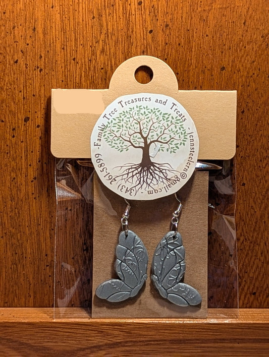 Pair of silver leaf earrings on a wooden surface with a price tag.